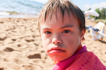 Beautiful Boy With Downs Syndrome Sitting at the Beachの写真素材