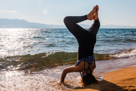 Young Woman Doing Handstand on the Sand at the Beachの写真素材