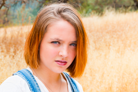 Beautiful Face of Girl With Read Hair Standing in Fieldの写真素材