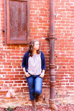 Young Girl Leaning Against Old Red Brick Wallの写真素材