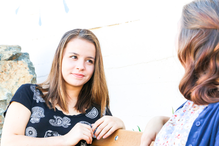 Two Young Girls Sitting on City Bench Togetherの写真素材