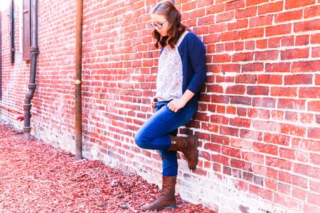 Young Girl Leaning Against Old Red Brick Wallの写真素材
