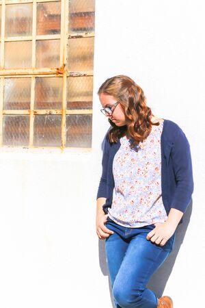 Beauiful Young Girl Leaning Against White Wallの写真素材