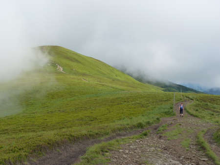 Foggy mountains. Trail in the mountains in the mist. Beautiful mountain landscape. Tourist climbing...