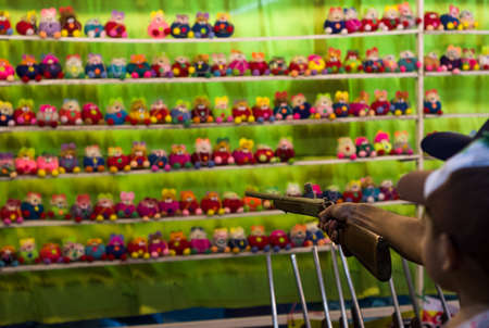 Carnival game shooting pop-caps at stuffed dolls for prize at festival in Thailandの写真素材