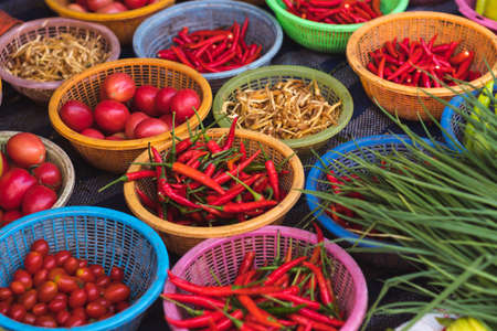 Variety of colorful peppers, tomatoes, ginger and greens in baskets for sale at local morning market in Sattahip, Thailandの写真素材