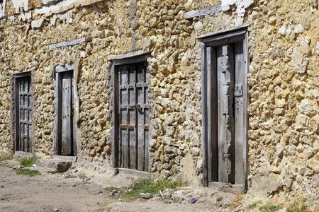 Old wooden doors in a stone wall of an old house in the villageの写真素材