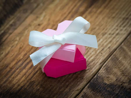 Two paper hearts with white ribbon on wooden backgroundの写真素材