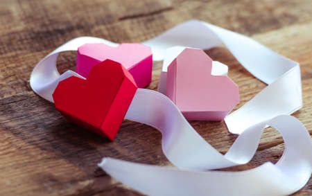 Bright paper hearts and white ribbon on wooden backgroundの写真素材