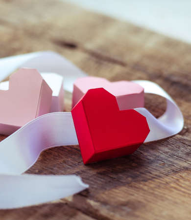 Bright paper hearts and white ribbon on wooden backgroundの写真素材