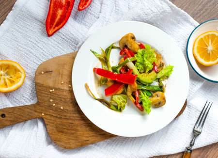 Bell pepper, avocado, mushrooms and leek salad on white plateの写真素材