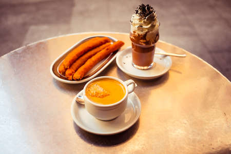 Coffee, churros and iced chocolate in spanish cafe. Toned in vintage colorsの写真素材