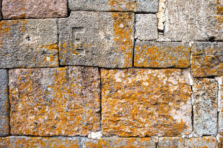 An old dry stone wall with brown moss and lichenの写真素材