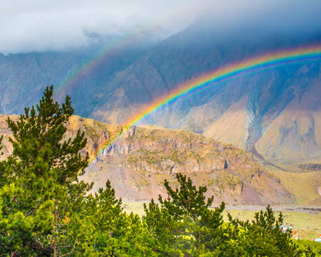 Bright rainbow after rain in Caucasus mountains near Kazbek (Kazbegi), Georgiaの写真素材