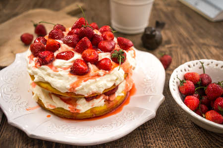 Strawberry cake with whipped cream in wooden table