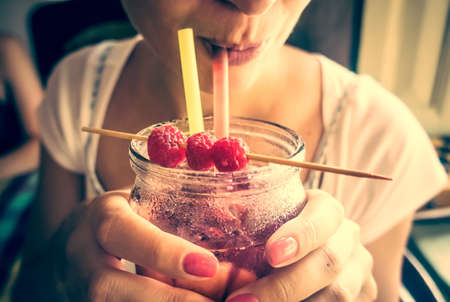 Young woman drinks fresh iced fruit lemonade. Toned picture