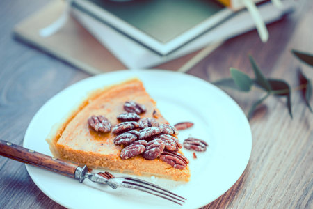 Pecan and pumpkin cake on plate with books on wooden background. Toned pictureの写真素材