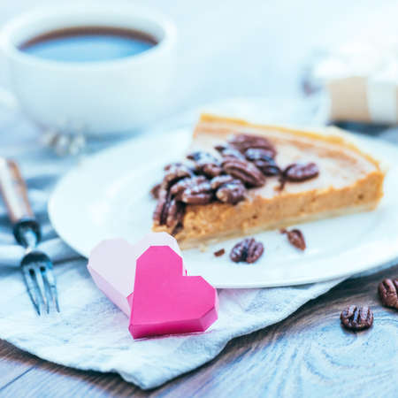 Paper hearts, gift box and pumpkin cake on wooden background. Toned picture