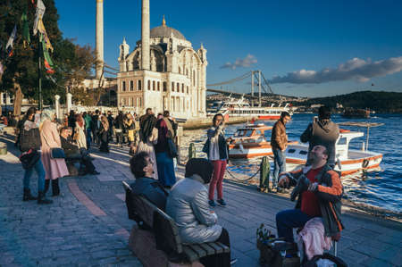 ISTANBUL, TURKEY -  october 23, 2014: people sre sitting on a bench in front of Ortakoy mosque in Istanbul, Turkey.のeditorial素材