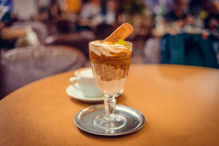 Ice cream dessert and cup of coffee  on the table in a cafe. Toned pictureの写真素材