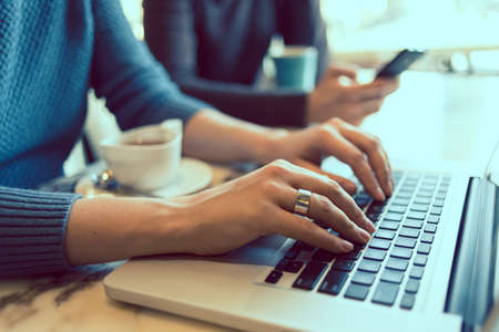 Female hands typing on the laptop keyboard in cafe. Toned pictureの写真素材