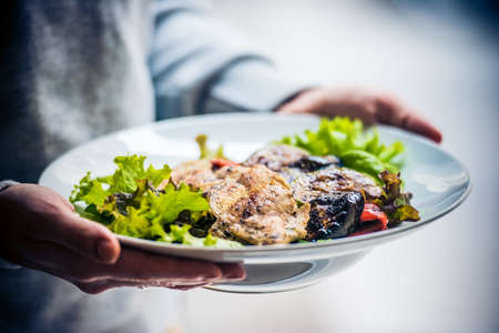 Grilled chicken and vegetables salad on white plateの写真素材