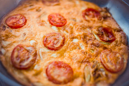 Omelette with leek and tomato and cheese. Frittata in a frying pan