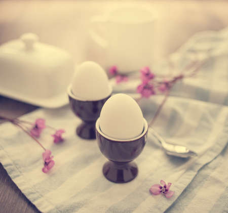 Two boiled eggs with bread and butter. Toned image