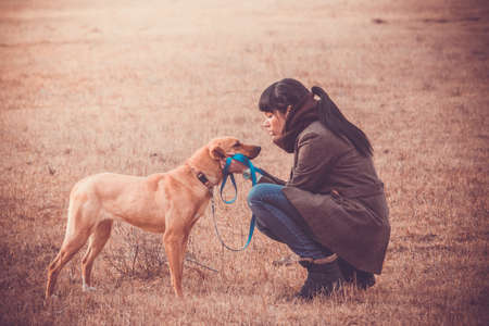 Pretty girl wailking with her dog. Toned imageの写真素材