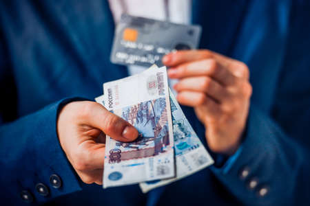 Business person holds russian roubles and plastic credit cardの写真素材