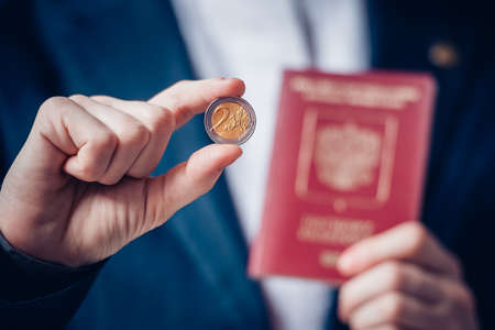Business person holds euro coin and russian passportの写真素材