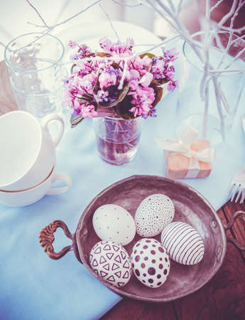 Modern painted easter eggs and spring violets on wooden table. Toned pictureの写真素材