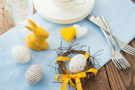 Modern painted easter eggs in a small nest on wooden table