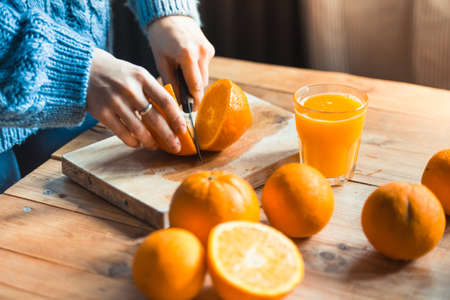 Person cutting  to make juice from fresh oranges on wooden tableの写真素材