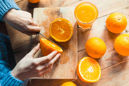 Person cutting  to make juice from fresh oranges on wooden tableの写真素材