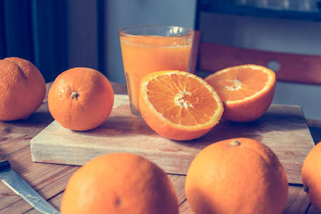 Fresh oranges and juice on wooden table. Toned pictureの写真素材