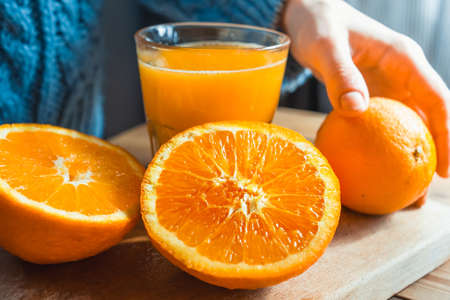 Fresh oranges and juice on wooden board in handsの写真素材