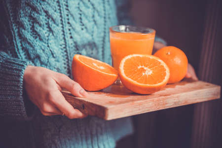 Fresh oranges and juice on wooden board in hands. Toned pictureの写真素材
