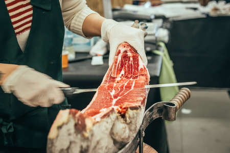 Slicing of italian dry-cured ham prosciutto. Toned image. Selective focus pointの写真素材