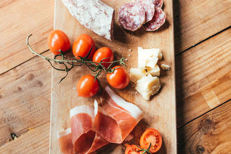 Appetizers - tomato, meat and cheese - on wooden boardの写真素材