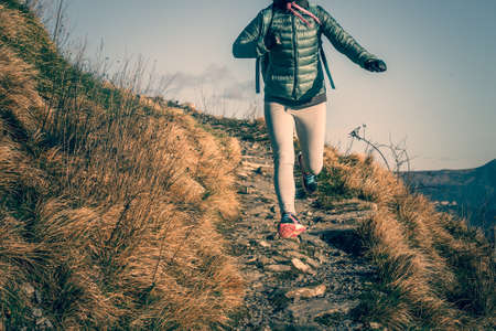 Walking or running young woman on trail in mountains. Toned pictureの写真素材