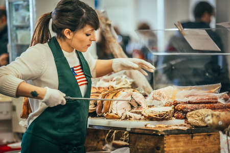 GENOA, ITALY - FEBRUARY 15, 2015: Unidentified butcher slicing italian pork roast porchetta at food market in Genoa, Italyのeditorial素材