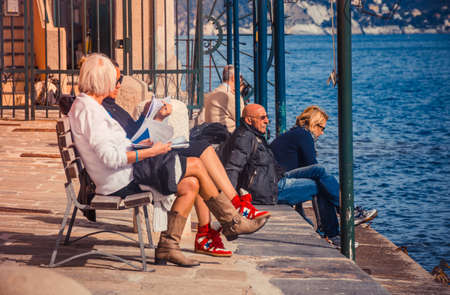 PORTOFINO, ITALY - FEBRUARY 27, 2015: People are sitting near the sea in Portofino. Portofino is an Italian fishing village famous for its picturesque harbor and celebrity visitorsのeditorial素材