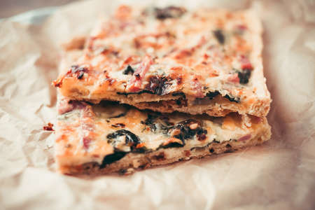 Two slices of quiche or pizza or focaccia on craft paper