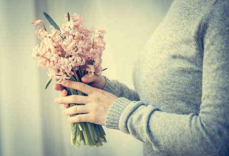 Young woman holding hyacinth flowers bouquet. Toned imageの写真素材