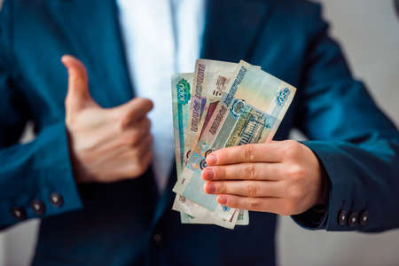 Business person holds roubles and shows thumb upの写真素材