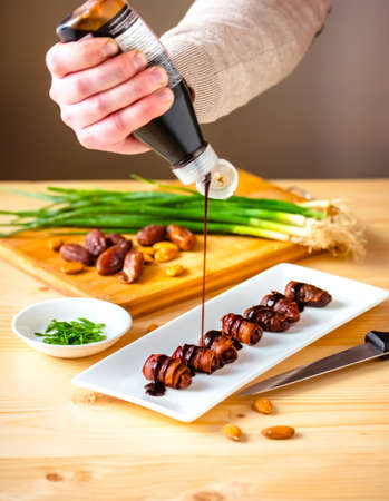 Snack appetizer - dried dates wrapped with bacon and dressed with balsamic creme vinegarの写真素材