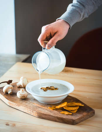 Plate of mushroom cream soup served with  toasts on wooden boardの写真素材