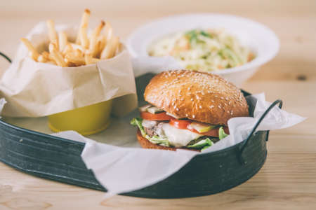 Lunch menu with classic american cheese burger, french fries and vegetable salad. Toned pictureの写真素材
