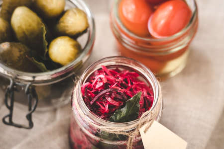 Different kinds of pickles - cabbage with beetroot, cucumbers and tomatoes in small jarsの写真素材